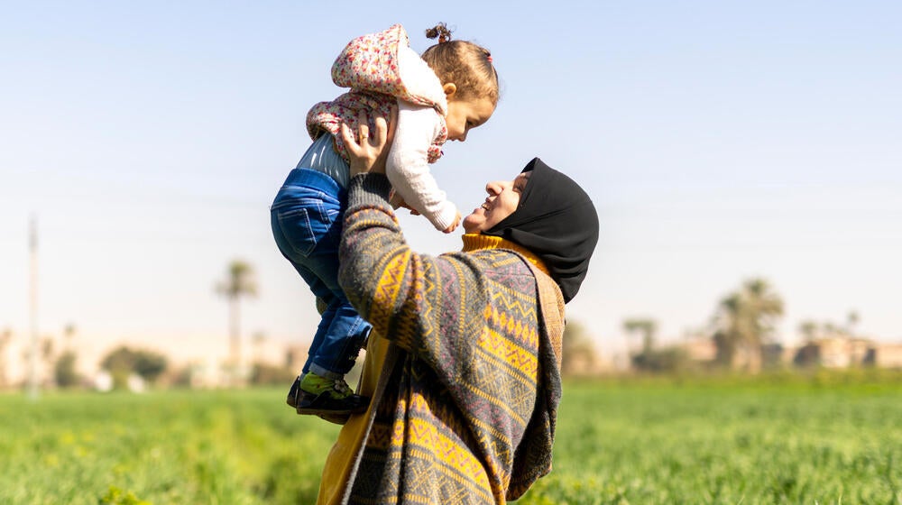 Woman happily holds a smiling child in the air.
